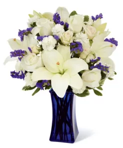 White Lily and Blue Flower Bouquet with white Asiatic lilies, ivory roses, cream spray roses, blue statice and dark blue vase