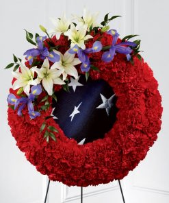 Patriotic American flag funeral wreath spray with blue iris red carnations white lilies flag inspired fabric and easel stand