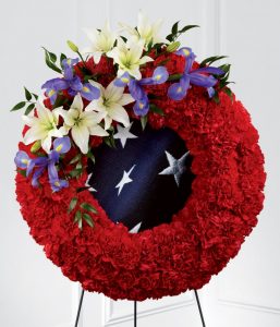 Patriotic American flag funeral wreath spray with blue iris red carnations white lilies flag inspired fabric and easel stand