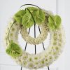 Double ring funeral standing spray with white chrysanthemums white button poms green anthurium and lily grass on easel stand