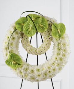 Double ring funeral standing spray with white chrysanthemums white button poms green anthurium and lily grass on easel stand