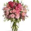Blushing rose and tulip bouquet with pink roses, hot-pink tulips, pale-pink carnations, waxflower and greenery in a glass vase
