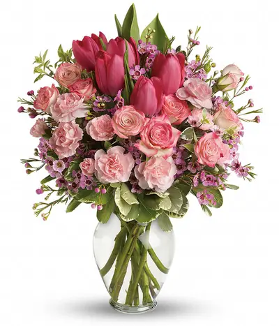 Blushing rose and tulip bouquet with pink roses, hot-pink tulips, pale-pink carnations, waxflower and greenery in a glass vase