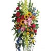 Vibrant Remembrance standing spray with pink yellow orange roses lilies sunflowers and blue delphinium